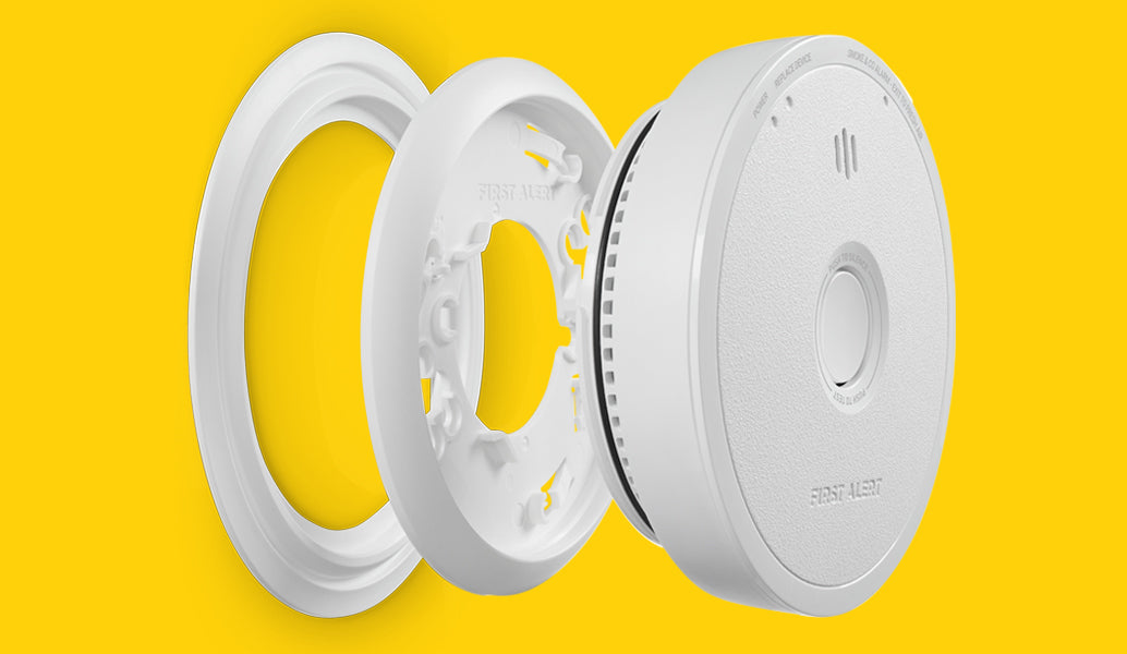 Parts of a smoke alarm shown separated, including the mounting ring and the alarm.